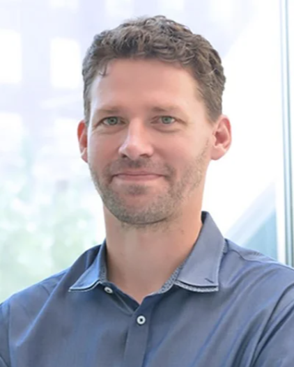 Headshot of Axel Krieger, a man smiling wearing a blue polo shirt
