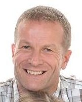 Headshot of Colin Wilkinson, a man smiling wearing a patterned shirt