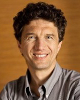 Headshot of Evgeni Gousev, a man smiling and wearing a gray collared shirt