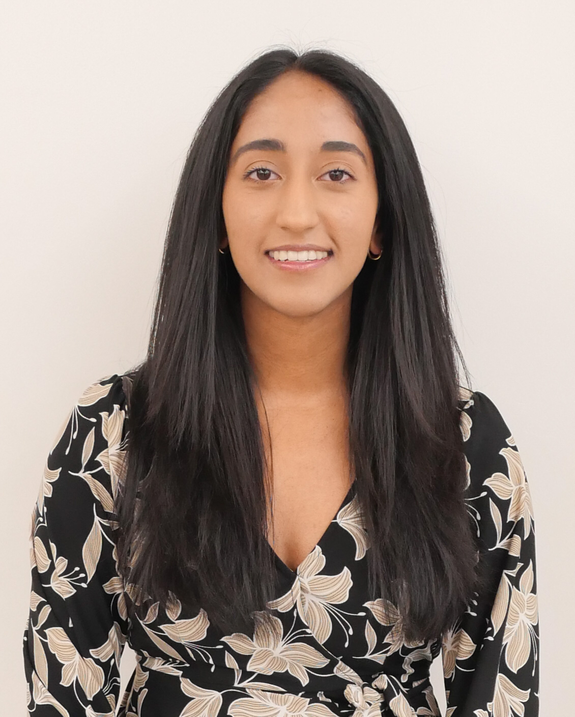 Headshot of Harsha Manivannan, smiling and wearing a black and gray patterned shirt
