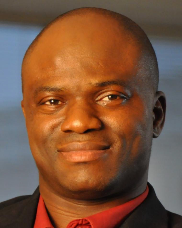 Headshot of Kingsley Fregene, a man smiling and wearing a red shirt