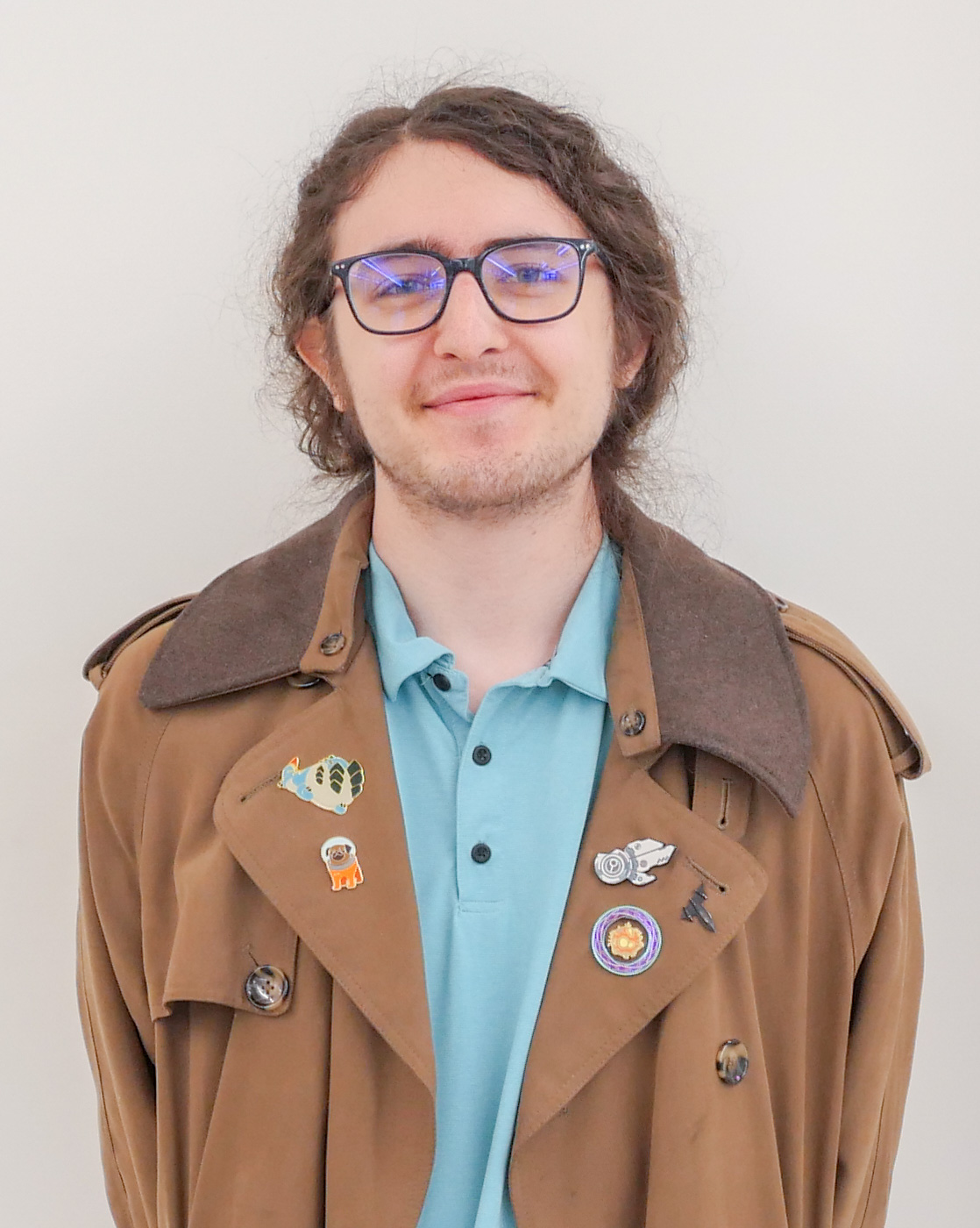 Headshot of Nate Herb, smiling and wearing black glasses, a blue shirt, and a brown jacket