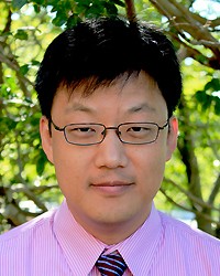 Headshot of Peter Chung, a man smiling wearing a pink shirt and striped tie
