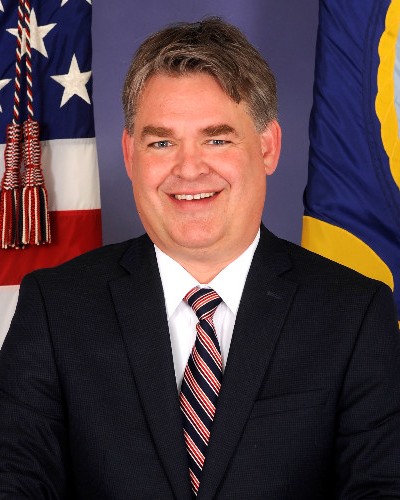Headshot of Rick Tarr, a man smiling wearing a dark jacket and striped tie