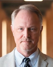 Headshot of Robert Hicks, a man wearing a light gray jacket, light blue shirt, and dark blue tie