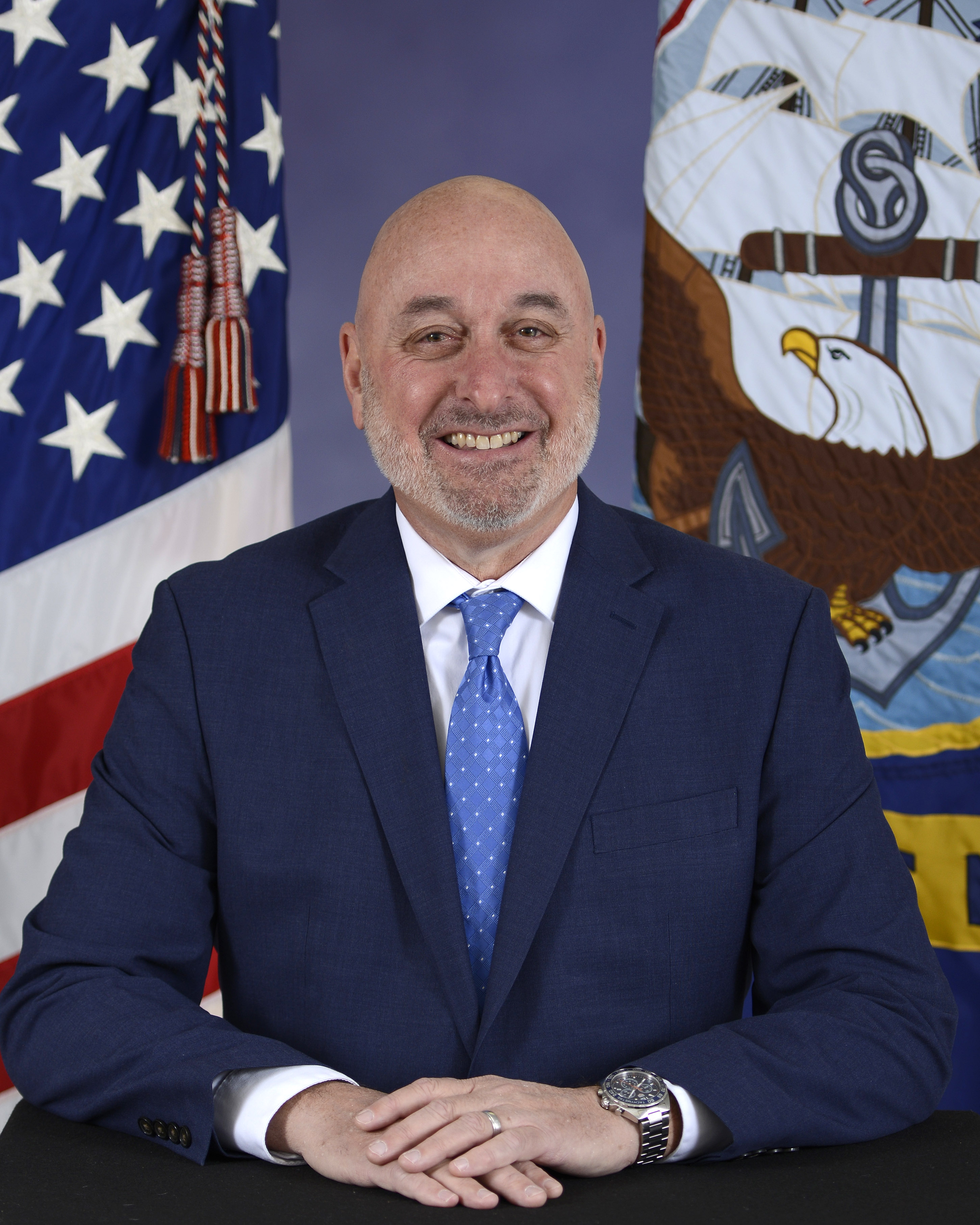 Headshot of Stephen Cricchi, a man smiling wearing a dark jacket and blue tie