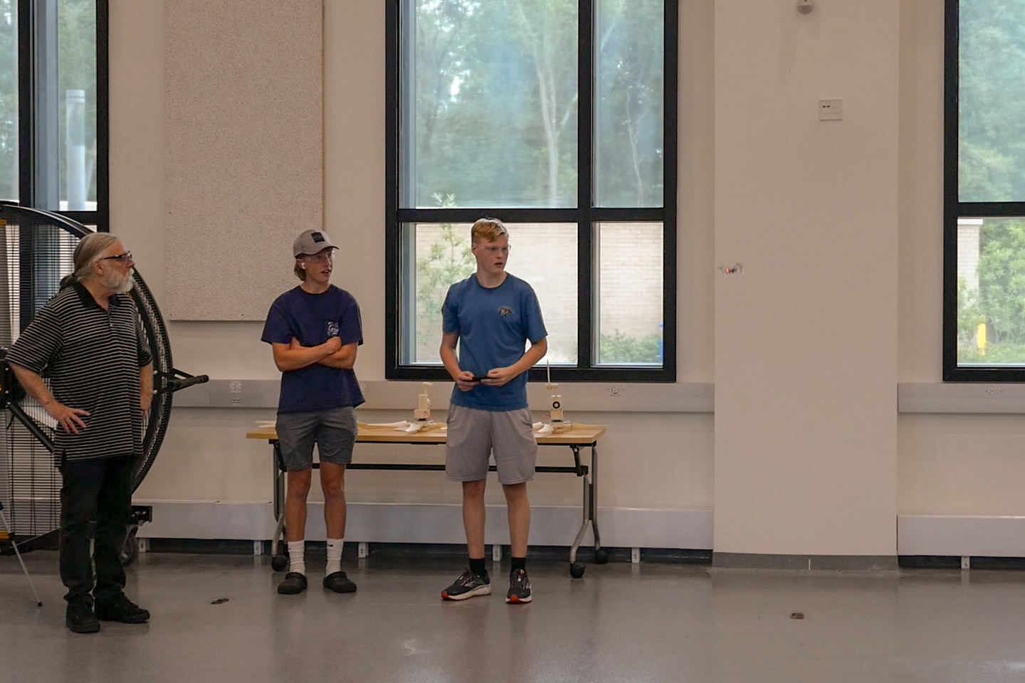 Camp participant flies drone while another camp participant and a camp instructor watch the drone