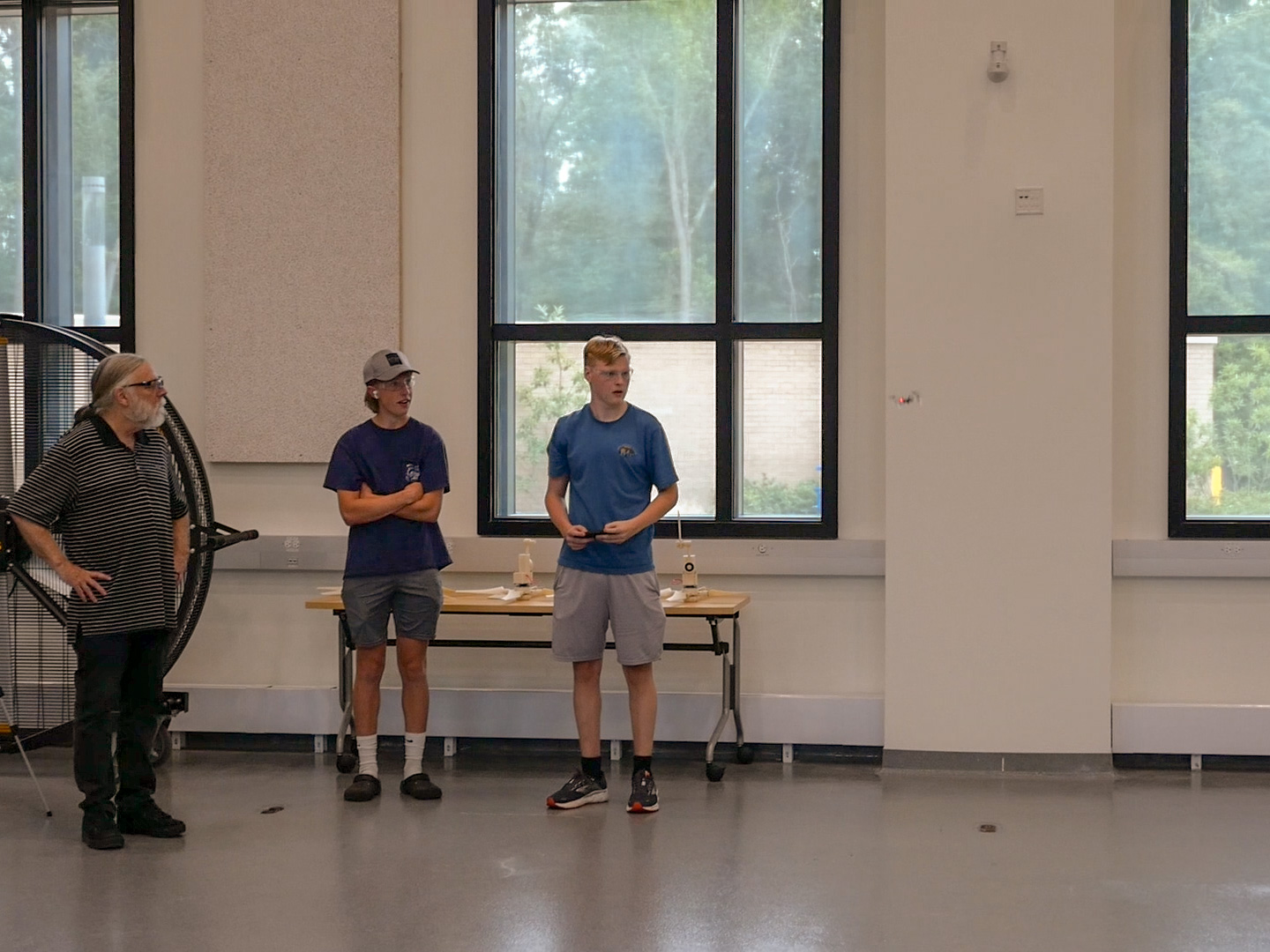Camp instructor and two camp participants fly small drone inside lab space