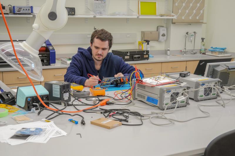Student works on breadboard surrounded by electronics