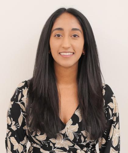 Headshot of Harsha Manivannan, smiling and wearing a black and gray patterned shirt