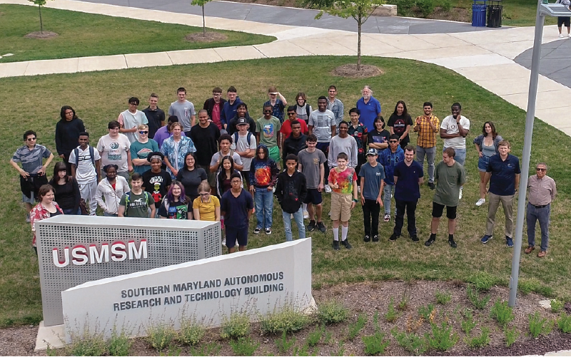 Group shot of 2023 summer camp participants behind sign that says Southern Maryland Autonomous Research and Technology Building